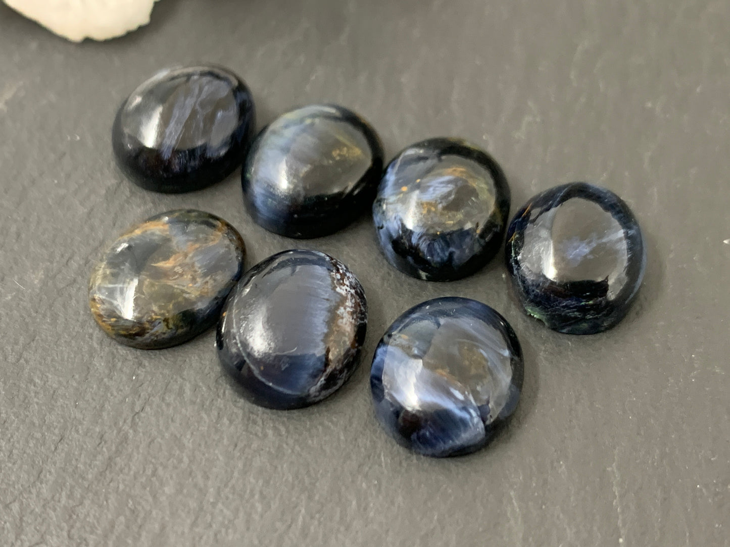a collection of dark blue gemstones, including amethyst, placed on a gray surface.