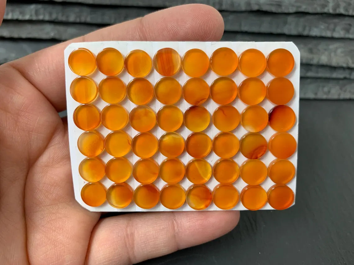 A hand is holding a white rectangular object with a grid of orange circular objects arranged in rows and columns.
