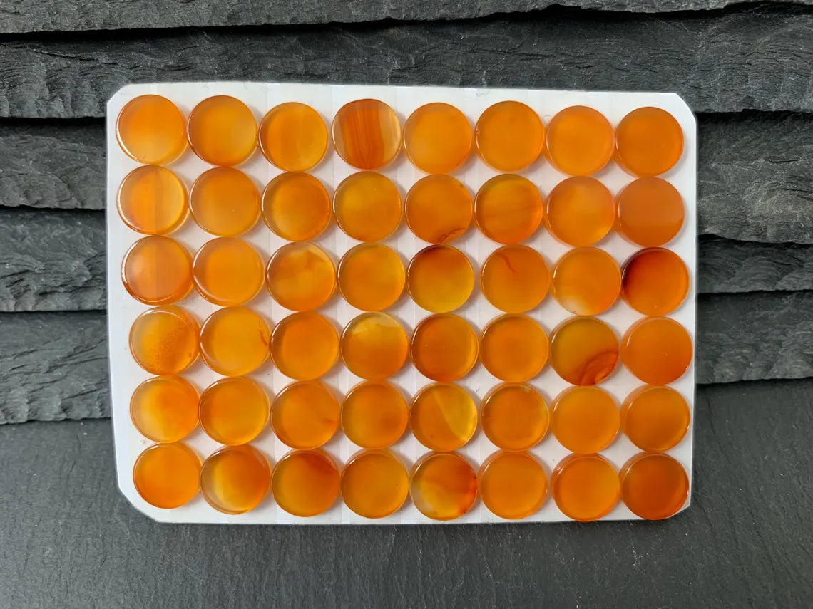 a collection of small, round orange glass beads arranged in a grid-like pattern on a white surface.