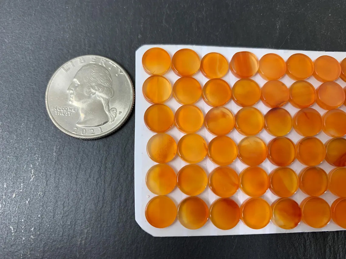 a silver quarter next to a white tray filled with small orange beads arranged in rows.