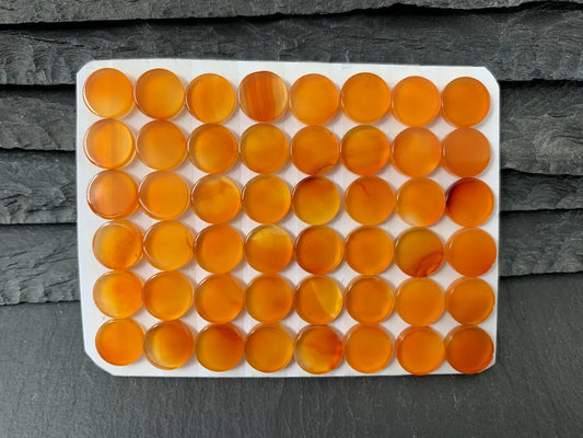 a collection of small, round orange glass beads arranged in a grid-like pattern on a white surface.