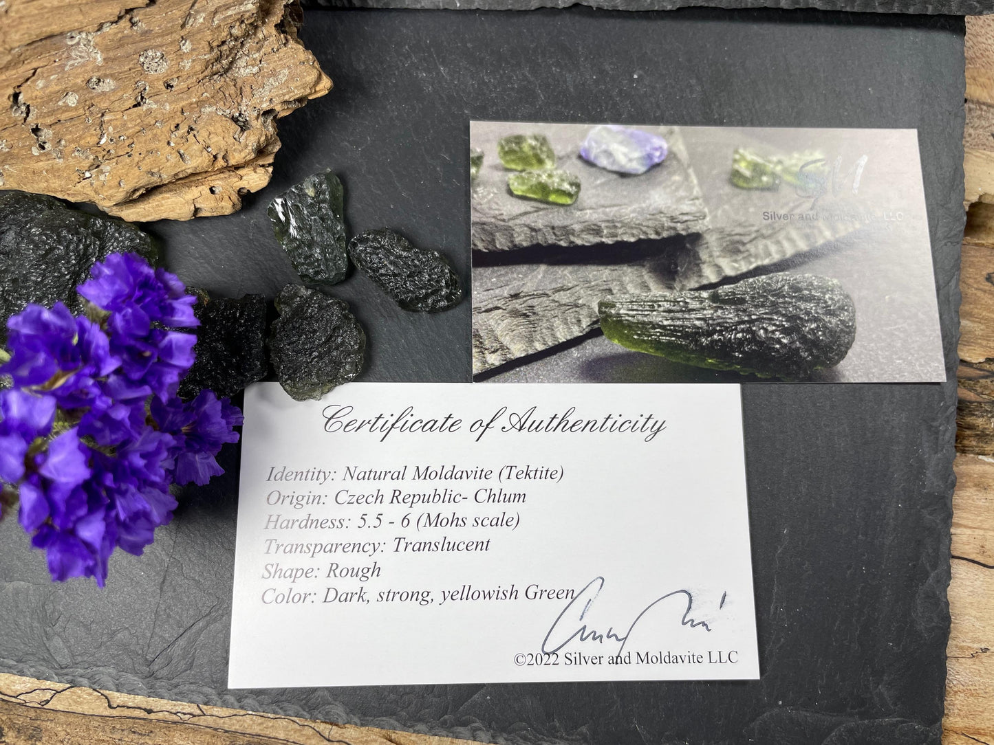a certificate of authenticity for a natural moldavite (tikite) gemstone, along with a photograph of the gemstone and some other natural elements.